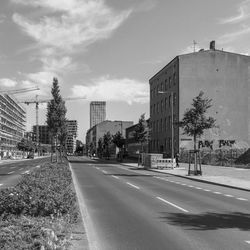 Road by buildings in city against sky