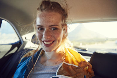 Smiling young woman on the back seat of a car