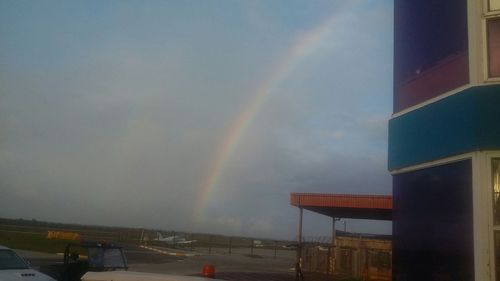 Rainbow over city against cloudy sky