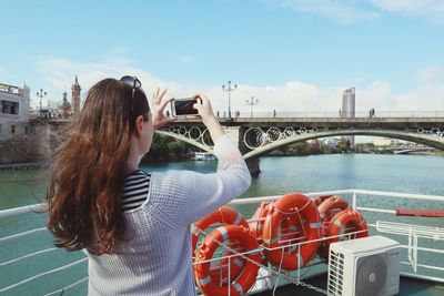 Woman on bridge against sky in city