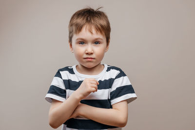 Portrait of cute boy standing against gray background