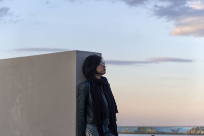 Rear view of woman standing against sea during sunset