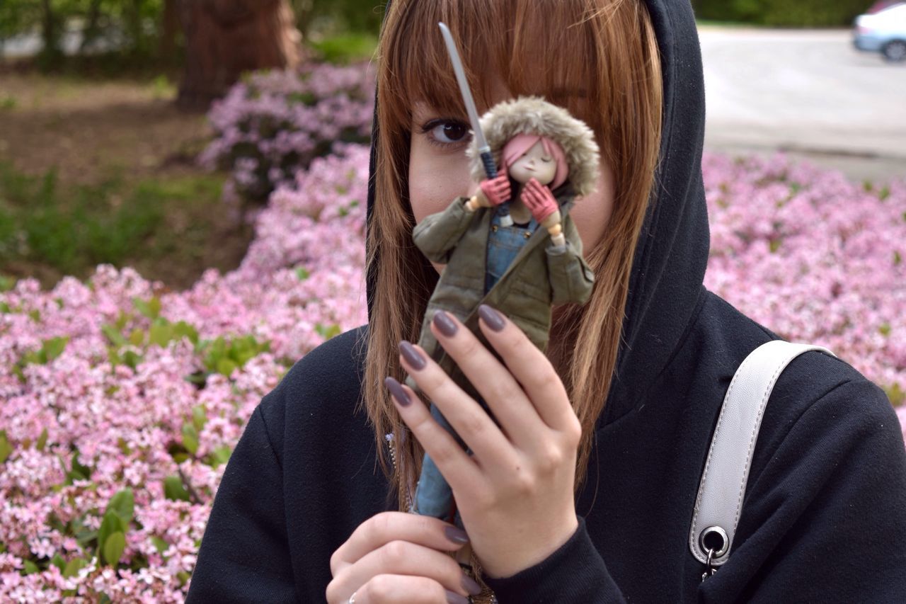 flower, holding, focus on foreground, lifestyles, leisure activity, person, young women, fragility, close-up, young adult, headshot, long hair, pink color, casual clothing, day, outdoors, people