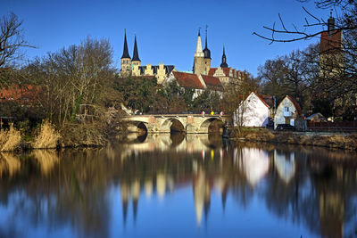 Arch bridge over river amidst buildings against sky