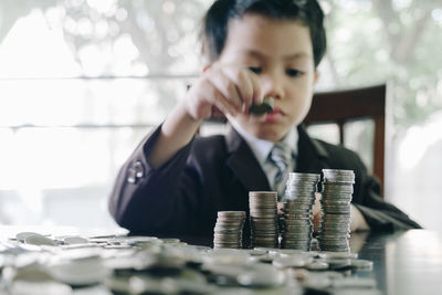 Cute boy stacking coins on table