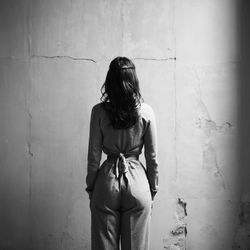 Young woman standing against wall