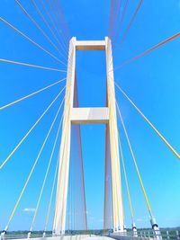 Low angle view of suspension bridge against blue sky