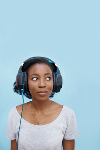 Young woman listening music against blue background