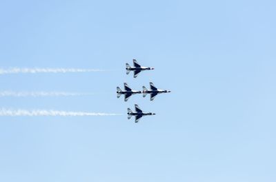 Low angle view of airshow against clear sky on sunny day