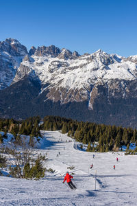 Person skiing on snowcapped mountains against clear blue sky