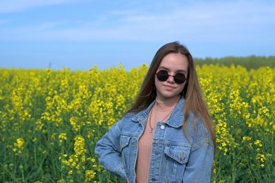 Portrait of beautiful young woman standing on field