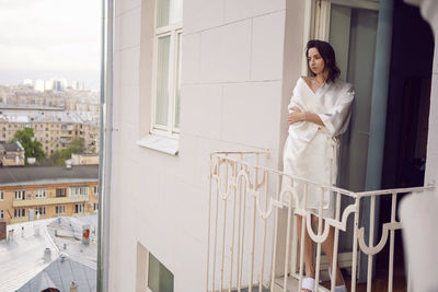Portrait of young woman standing by window