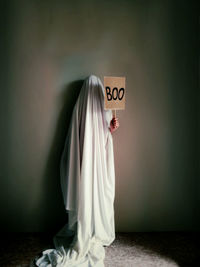 Person standing in halloween ghost costume holding sign