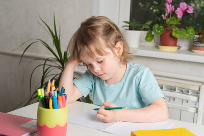 Back to school. girl sits at a table with books and a notebook and does her homework. 