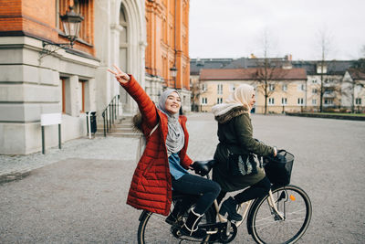 Woman riding bicycle on street against buildings in city