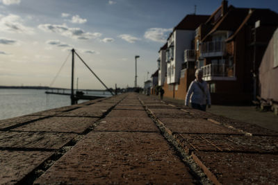 View of walkway amidst buildings against sky