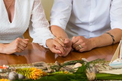 Midsection of woman holding hands on table