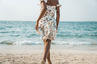 Woman standing on beach against sea