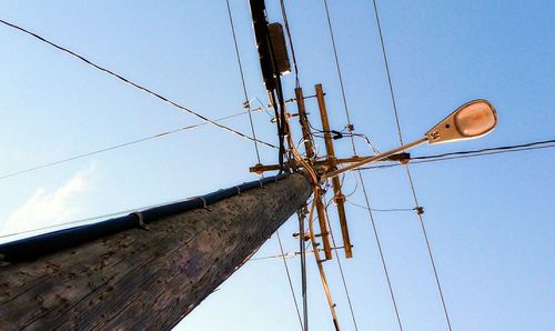 Low angle view of electricity pylon against blue sky