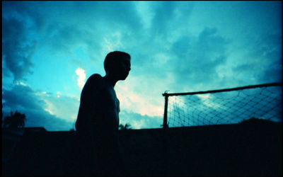 Low angle view of silhouette man standing against blue sky