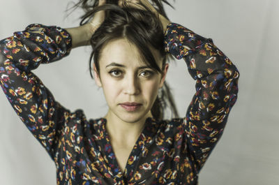 Portrait of woman with hands in hair against white background