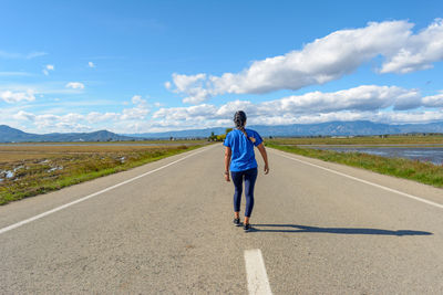 Latina woman walking along lonely road center in the ebro delta natural park, catalonia, spain