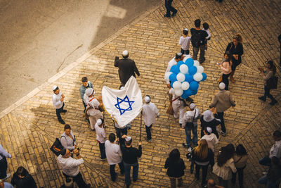 High angle view of people carrying israeli flag and balloons on footpath