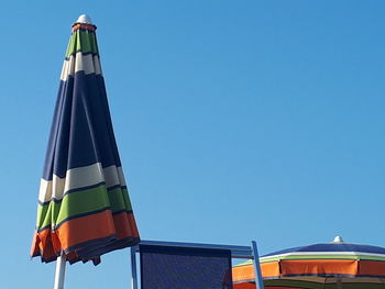 Low angle view of flags against clear blue sky