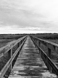 Boardwalk on landscape against sky