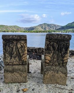 View of stone structure in water against cloudy sky