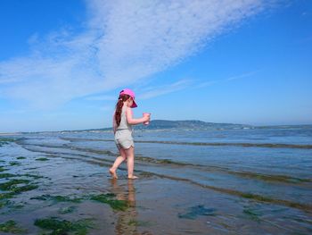 Girl walking at beach against sky