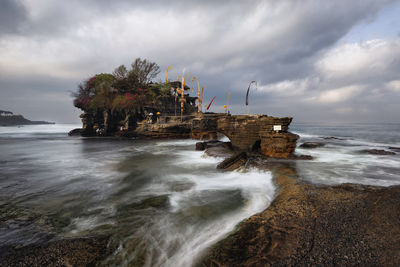 Rock formation on beach against sky