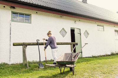 Woman arranging work tools against barn at farm