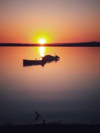 Silhouette boat in lake against sky during sunset