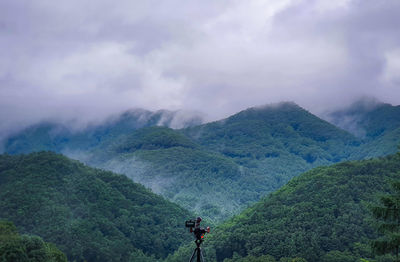 Rear view of man standing on mountain against sky