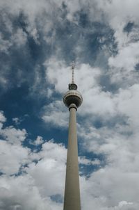 Low angle view of communications tower against cloudy sky