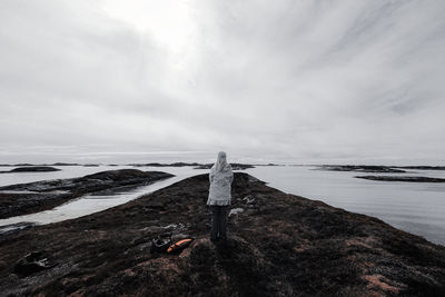 Rear view of man walking on beach against sky