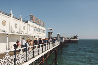 People on palace pier over sea against clear sky