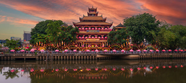 Illuminated buildings in water at sunset