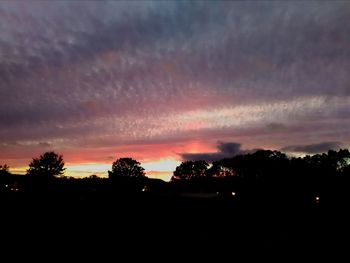 Silhouette trees against dramatic sky during sunset