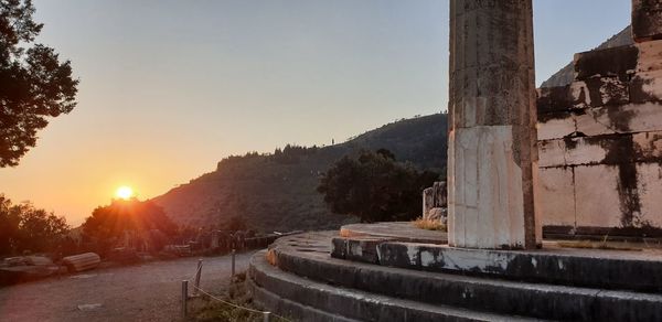 Walkway by buildings against sky during sunset