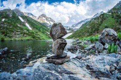 Stack of rocks by lake against sky