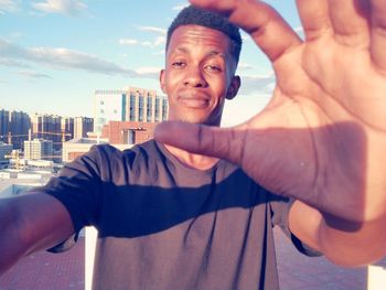 Portrait of smiling man gesturing while standing in city