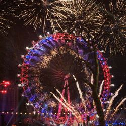 Low angle view of illuminated fireworks against sky at night