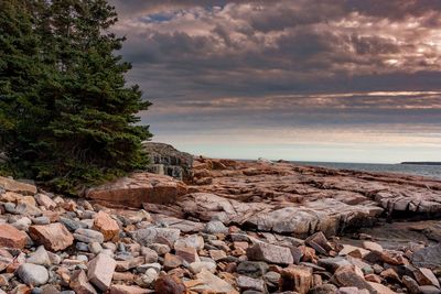 Rocks by sea against sky during sunset