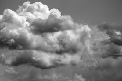 Low angle view of airplane flying against cloudy sky