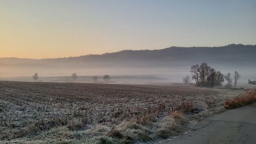 Scenic view of snowy field against sky during sunset