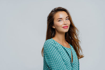 Portrait of young woman standing against white background