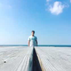 Close-up of wooden table against man standing at beach