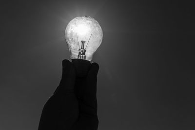 Low angle view of illuminated light bulb in darkroom